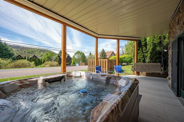 Un bain à remous situé sous une terrasse couverte, avec vue sur une route et des maisons.