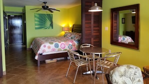 Una habitación con cama, una mesa, sillas, ventilador de techo y espejo.