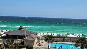 A beachside view with a pool, umbrellas, and ocean waves. - One bedroom one bath oasis! Enjoy one free beach chair set up daily. (Destin)