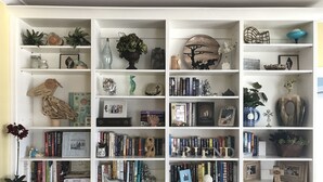A white bookshelf with various decorative items, books, and small sculptures. - Luxury Beachfront Home, with Ramp; Sleeps up to 18! (Gulf Shores)