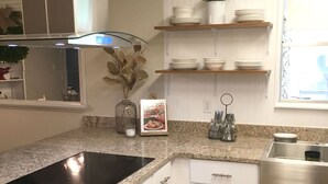 Une cuisine moderne avec des armoires blanches, un comptoir en granit, un évier en acier inoxydable et une fenêtre offrant une belle vue.