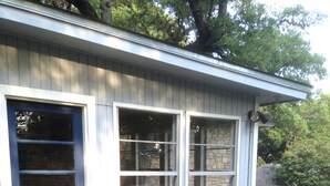 Une maison avec une porte bleue, une façade en pierre et une terrasse avec une table et des chaises.