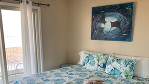 Un dormitorio con cama, ventilador de techo, un cuadro y vistas al exterior.