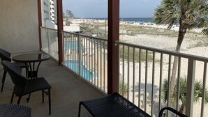 Un balcón con vistas a la playa, una piscina y una palmera.