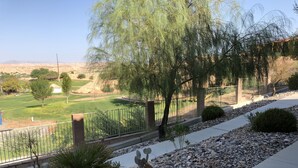Zona ajardinada con un sendero, un cactus y vistas a un campo de golf.