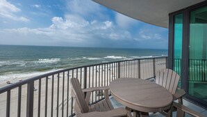 A balcony with a table and chairs overlooking the beach and ocean. - Phoenix IX 905 - Beautiful 3BR Gulf Front Unit (Orange Beach)