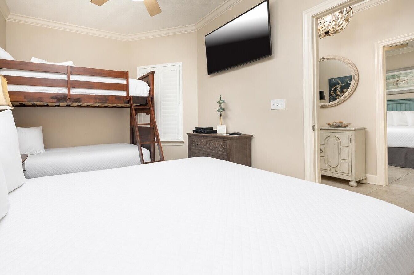 A bedroom with a bunk bed, a flat-screen TV, a dresser, and a mirror.