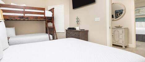A bedroom with a bunk bed, a flat-screen TV, a dresser, and a mirror.