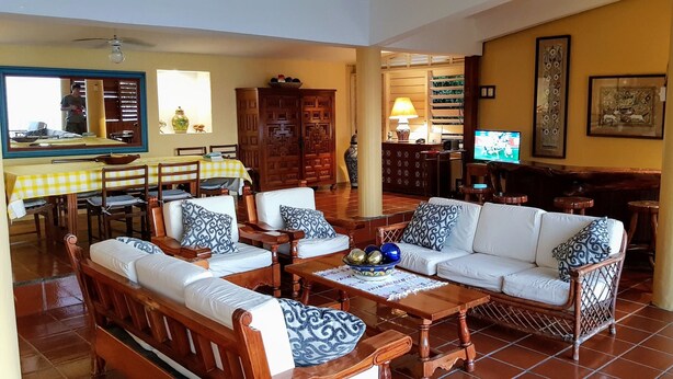 Un salón amplio con comedor, un conjunto de sofás, un televisor y un gran armario de madera.