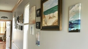 A hallway with artwork on the walls, a wooden beam ceiling, and a tiled floor. - Beach Front Sleeps 10 Walking distance to everything (St. George Island)