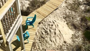 A wooden boardwalk leading to a sandy beach area with a wooden deck and chairs. - Beach Front Sleeps 10 Walking distance to everything (St. George Island)
