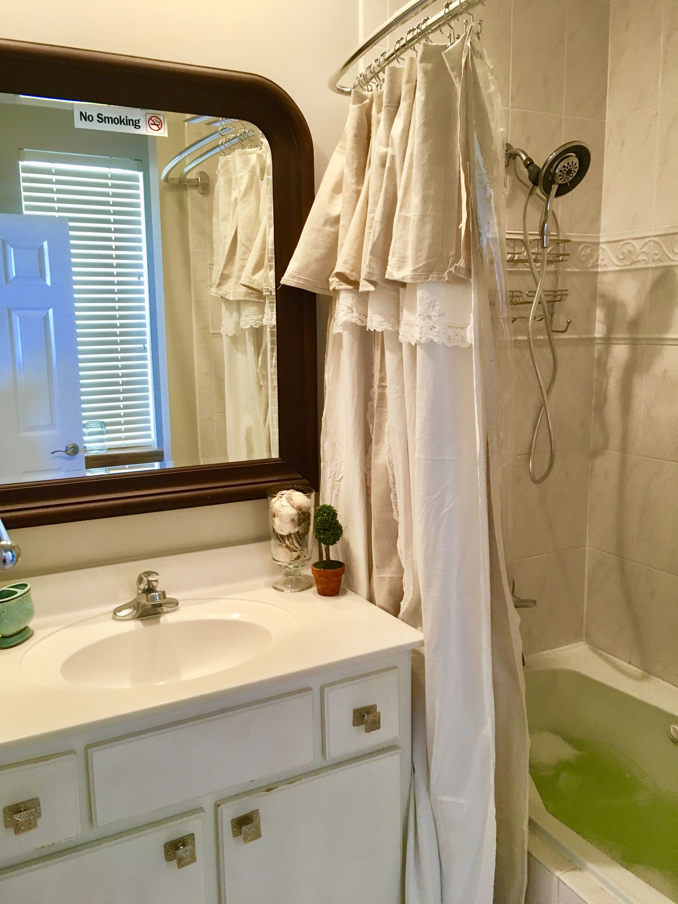 A bathroom with a white sink, a mirror, a shower curtain, and a bathtub.