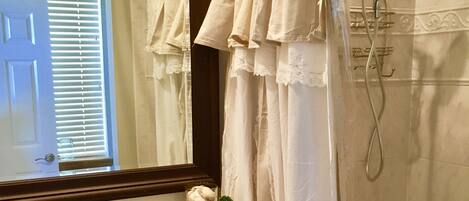 A bathroom with a white sink, a mirror, a shower curtain, and a bathtub.