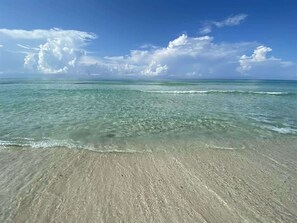 A beach with clear water and a sandy shore.