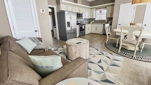 A living room with a sofa, a round wooden coffee table, and a dining area with a table and chairs. - Walk to Beach or Pool-2 Bikes/Match Pointe CH (Santa Rosa Beach)