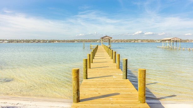 A wooden pier leading to a small wooden structure on a clear day.