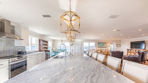 A spacious kitchen with a large marble island, modern appliances, and a unique chandelier.