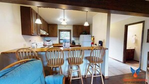 A kitchen with wooden cabinets, a bar stool seating area, and a dining table. - Close to Lifts | Fireplace | Views | Ski Run B6 (Angel Fire)