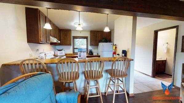 A kitchen with wooden cabinets, a bar stool seating area, and a dining table.