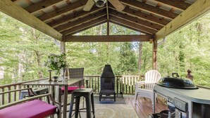 A covered outdoor area with a grill, seating, and a view of the forest. - Walk to Main *Outdoor Games* Pet Friendly* Fairy Trail (Saluda)