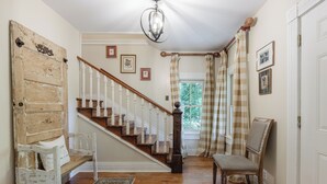 A staircase with white railings and a wooden handrail, leading to a landing with a bench and a chair. - Walk to Main *Outdoor Games* Pet Friendly* Fairy Trail (Saluda)