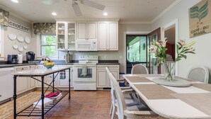 A kitchen with white cabinets, a microwave, a stove, and a dining table with chairs. - Walk to Main *Outdoor Games* Pet Friendly* Fairy Trail (Saluda)