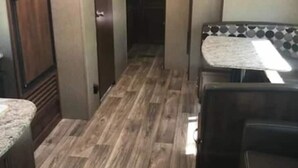 Interior compacto de autocaravana con kitchenette, baño pequeño y zona de estar.