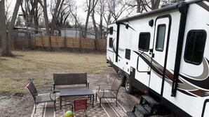 Una caravana con una mesa de picnic y sillas en un patio trasero.