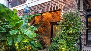 Ein Backsteinhaus mit Balkon und gepflegtem Garten.