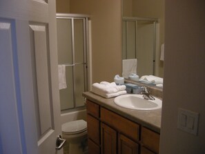 A bathroom with a toilet, sink, and shower. There are towels and toiletries on the counter. - Mesquite Nevada Condominium Vacation Rental Ground Level (Mesquite)