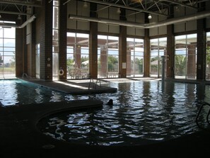 Une piscine intérieure offrant une vue dégagée sur l’extérieur grâce à de grandes fenêtres.
