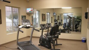 Un gimnasio con máquinas de cardio, espejos y equipo de ejercicio.