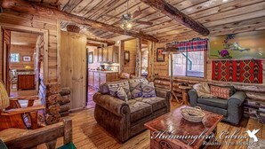 A rustic cabin interior with wooden walls and ceilings, a fireplace, a sofa, a coffee table, and a television. - Happy Bears Cabin | Beary Cozy Getaway w/ Fireplace & Forest Views (Ruidoso)