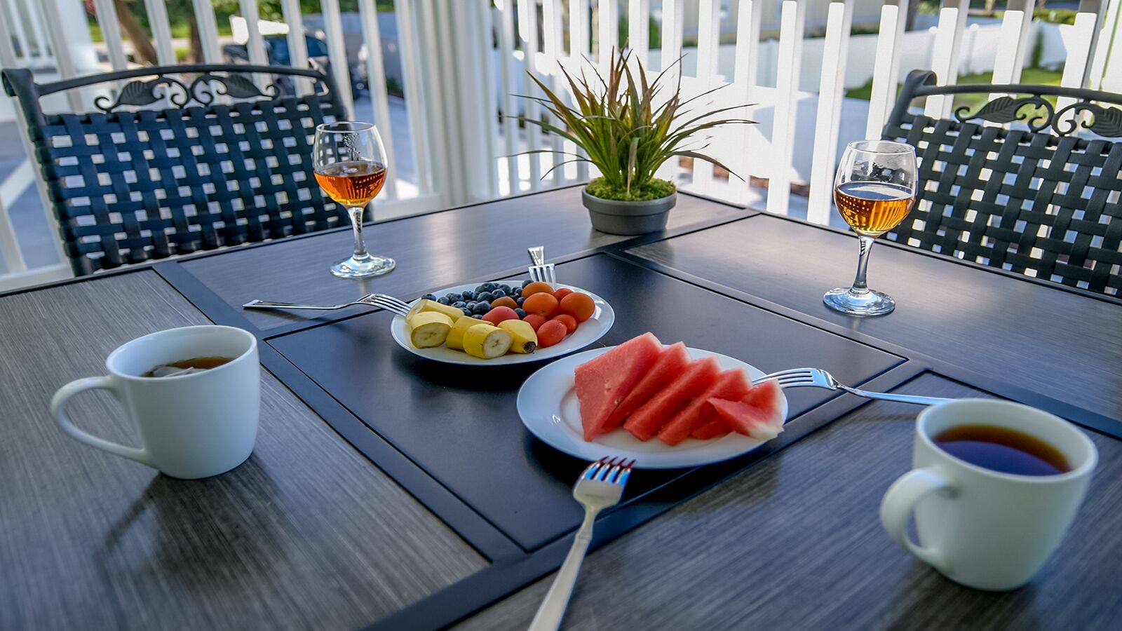 A table set with a plate of fruit, two glasses of a beverage, and a cup of coffee.
