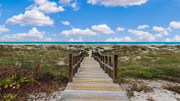 A wooden boardwalk leading to a beach with a clear sky and clouds. - Turtle Dunes Oceanfront Ground floor 2br/2ba (Amelia Island)