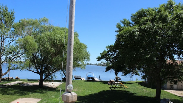 A lakeside park with a swing set, a boat dock, and a gazebo.
