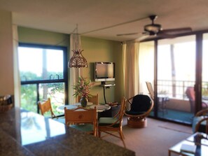 A modern living room with a dining area, a television, and a large window.