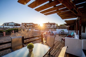 Relax in a shaded patio area with comfortable seating and a dining table.