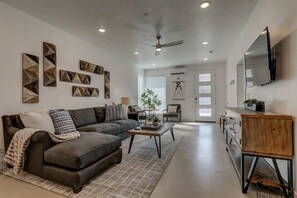 A modern living room with a sofa, coffee table, and decorative wall art. - The Lofts #5 | Townhome Pool Resort | Poolside (Saint George)