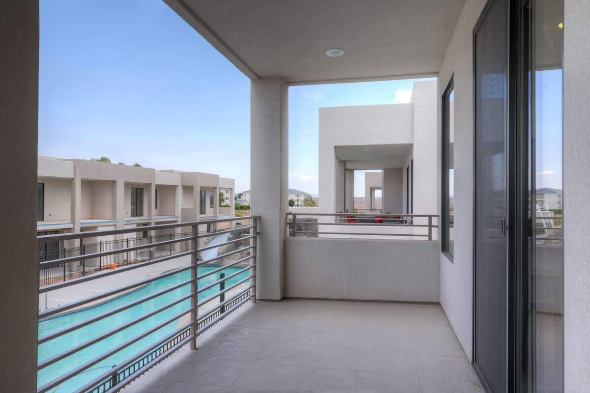 Een balkon met uitzicht op een zwembad en omliggende gebouwen.