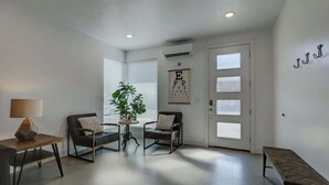A room with a desk, two chairs, a plant, and a door with frosted glass panels.