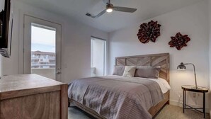 A bedroom with a bed, a bedside table, a ceiling fan, and a window.