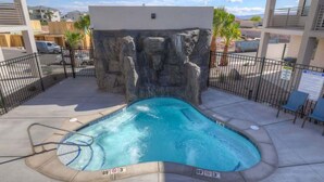 A swimming pool with a rock wall backdrop, surrounded by a fence, and a sign indicating a depth of 3 feet.