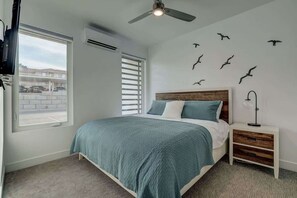 A bedroom with a bed, a nightstand, a ceiling fan, a window, and wall-mounted bird decorations. - The Lofts #5 | Townhome Pool Resort | Poolside (Saint George)