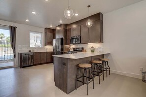 A modern kitchen with a central island, bar stools, and pendant lighting. - The Lofts #5 | Townhome Pool Resort | Poolside (Saint George)