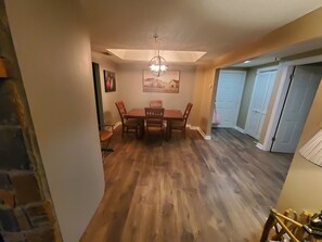 A dining area with a wooden table and chairs, a chandelier, and a painting on the wall.