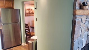 A kitchen with a stone fireplace, wooden cabinets, and a stainless steel refrigerator. - Affordable Rate with a Priceless View! (Sugar Mountain)
