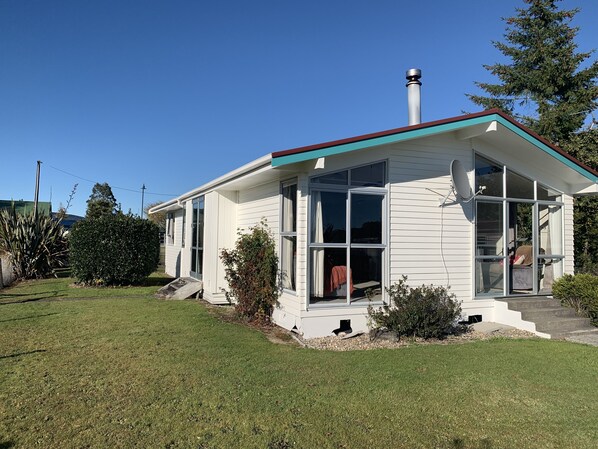 A single-story house with a white exterior, a red roof, and a chimney. It has large windows and a visible satellite dish. - Turquoise Lodge, National Park  36 Carroll Street National Park (National Park)
