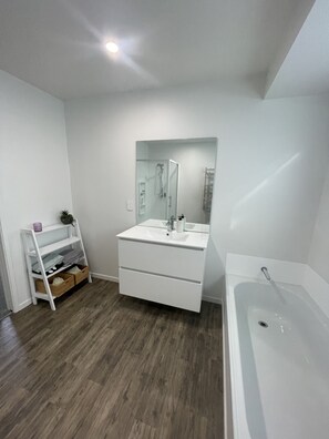 A modern bathroom with a white vanity, a large mirror, a bathtub, and a wooden floor. - Turquoise Lodge, National Park  36 Carroll Street National Park (National Park)