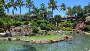 A resort with a pool, palm trees, and a rocky island.